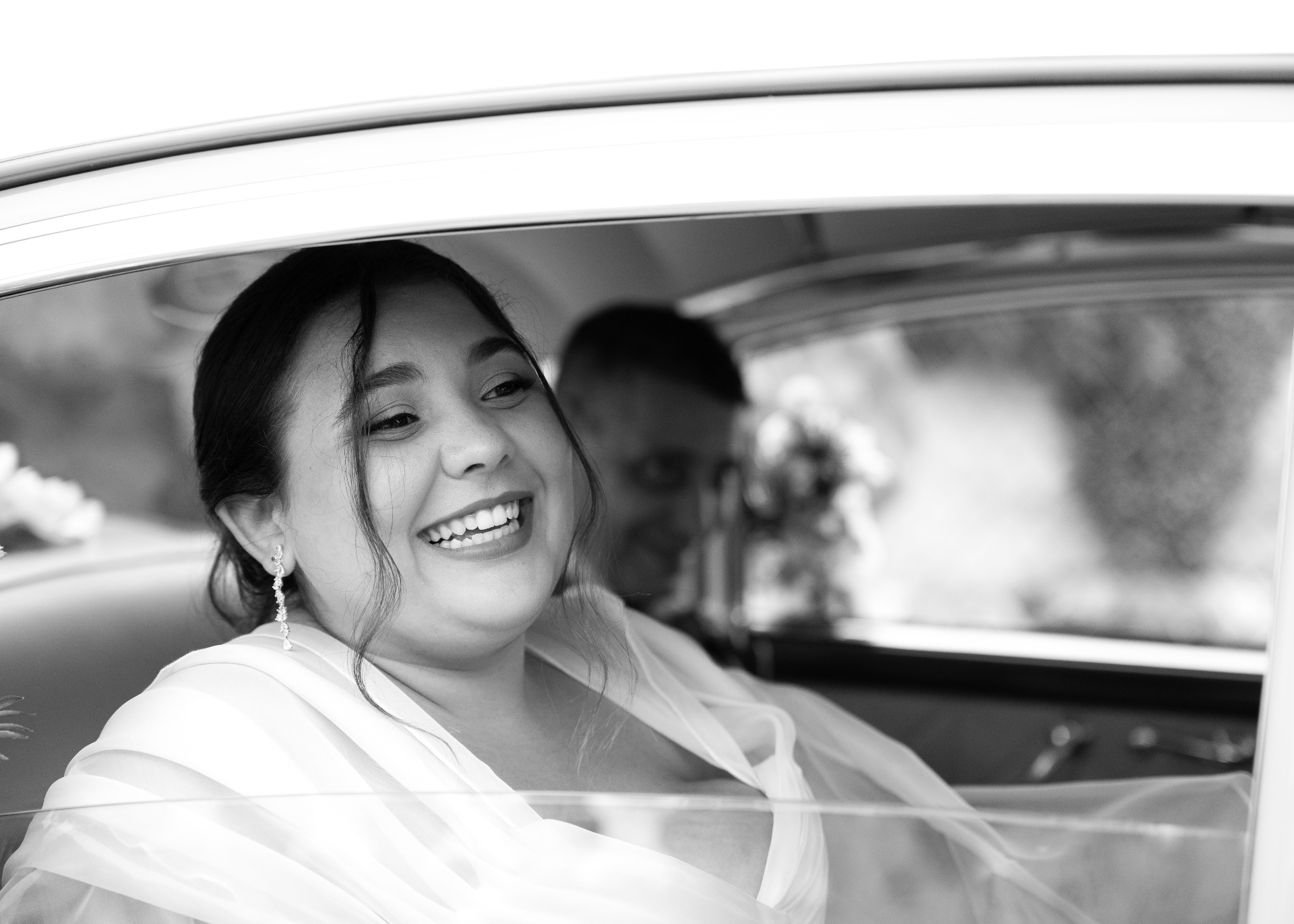 Novia sonriendo desde el coche nupcial